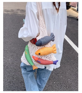 Close-up of white crochet tote bag featuring five colorful plush fish-shaped charms