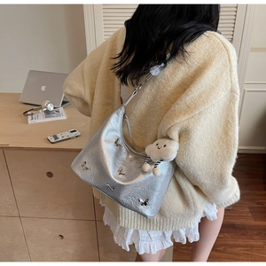Vue latérale détaillée du sac hobo argenté avec papillon métallique et charm nuage