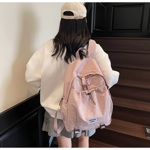 Detail of light pink nylon backpack with drawstring pocket and adjustable shoulder straps