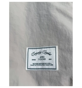 Close-up of durable light gray canvas fabric and white AVEC YOUNG logo patch stitching