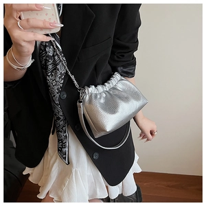 Borsa a mano argento con catena abbinata a blazer nero e abito per un look alla moda