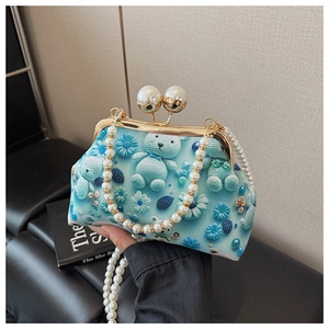 Close-up of blue mini shell bag with cartoon bear print and large pearl closure