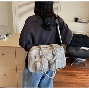 Dettaglio borsa da viaggio grigia con texture in pelle, tasche multiple e doppi manici