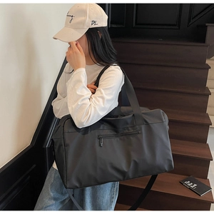 Borsa da viaggio nera minimalista indossata da una modella con grande capacità