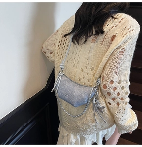 Close-up of silver sequin crescent bag with chain strap and star charm on model