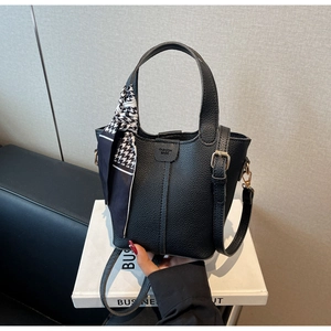 Detail of black pebbled leather bucket bag featuring fashion embossing and houndstooth scarf