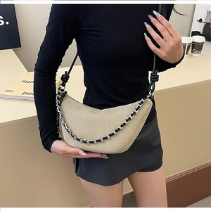 Detail of khaki crescent crossbody bag featuring silver chain and adjustable strap