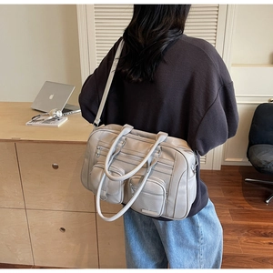 Vista laterale della borsa tote grigia multitasche in tela indossata da una modella