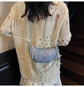 Detail of silver-blue crescent moon bag with metallic finish and chic chain strap