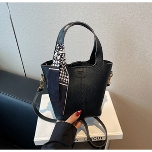 Detail of black lychee grain leather bucket bag with houndstooth silk scarf handle
