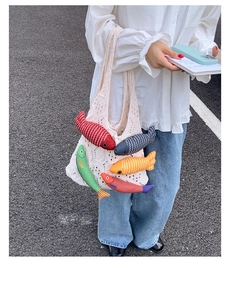 Detailed close-up of a white knit tote bag with colorful 3D plush fish decorations