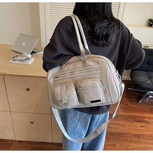Dettaglio della grande borsa beige in pelle con doppie tasche con zip e tracolla