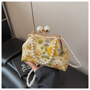 Close-up of beige shell bag featuring bear patterns and dual pearl clasp detail