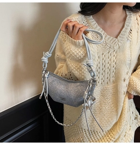Silver glitter crescent bag featuring a knotted leather strap and decorative metal chain