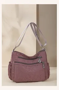 Detail of dusty rose quilted nylon crossbody bag with multi-zippered pockets