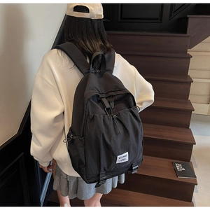 Detail of black nylon backpack featuring drawstring closure and white logo patch