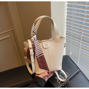 Close-up of beige leather bucket bag with fashion lettering and houndstooth silk scarf