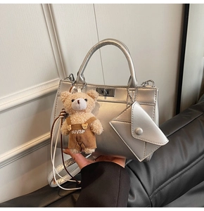 Détail du sac à main argenté métallisé avec breloque ours brun et mini pochette