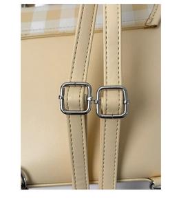 Detail of light beige faux leather straps with silver square adjustable buckles and stitching