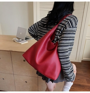 Vista posteriore di una modella che indossa una grande borsa tote rossa in pelle