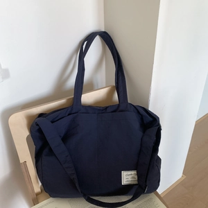Detail of a navy blue canvas tote bag with adjustable shoulder strap and vintage cloth label