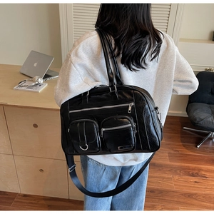 Vista dettagliata della borsa a spalla nera con design multitasche e tracolla larga