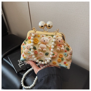 Detail of hand-knitted shell bag with 3D teddy bear charm and pearl chain strap