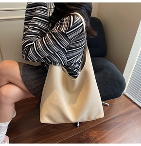 Dettaglio della grande borsa Hobo crema con trama martellata in un ambiente accogliente