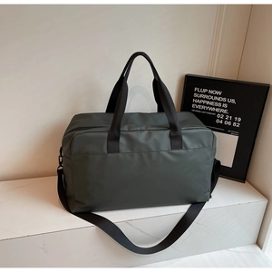 Dettaglio borsa da viaggio in nylon verde scuro con manici e tracolla su marmo