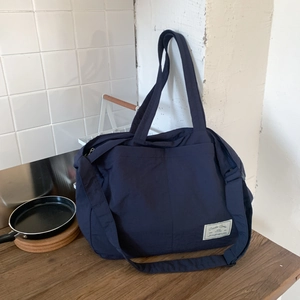 Detail of navy blue canvas tote bag with adjustable shoulder strap and woven brand label