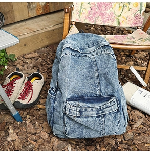 Close-up of retro washed denim backpack with front pocket in an outdoor setting