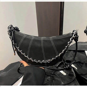 Detail of black leather crescent bag with white contrast stitching and silver chain strap