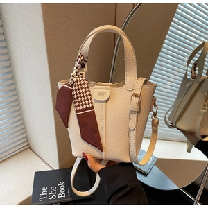 Detail view of cream bucket bag with silk scarf handle and lychee grain texture