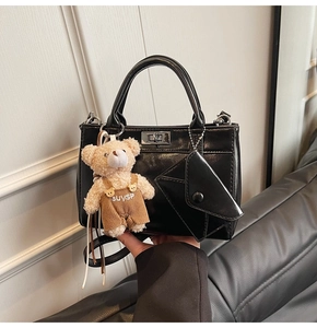 Détail du sac à main noir en similicuir avec fermoir rotatif et charm ours mignon