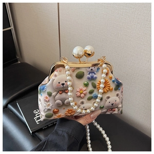Detail of vintage shell bag with cartoon bear print, pearl handle and gold metal frame clasp