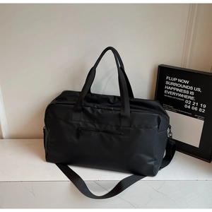 Dettaglio macro della borsa da viaggio in nylon nero su fondo in marmo bianco