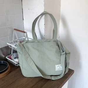 Detail of sage green nylon tote bag with adjustable strap and casual woven label
