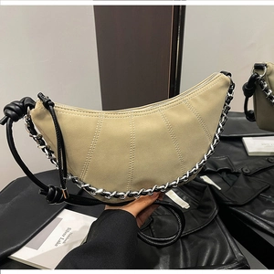 Detail of beige crescent shoulder bag with silver chain and knotted black leather strap