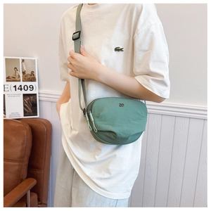 Detail of pea green nylon crossbody bag showing the D logo and double zipper texture