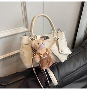 Détail du sac à main en cuir blanc crème avec mini pochette et charm ours en peluche