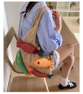 Close-up of beige crochet tote bag featuring five colorful plush fish-shaped pendants
