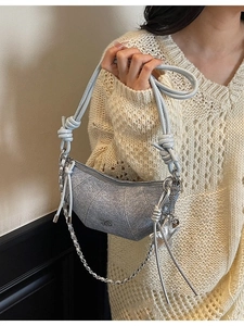 Silver crescent hobo bag with knotted strap and metal chain detail on model