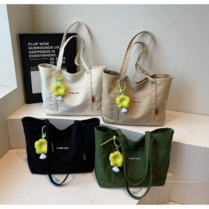 Dettaglio di borse tote in tela in quattro colori con ciondoli a fiore su display