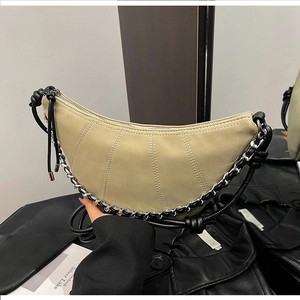 Detail of khaki crescent bag with vertical quilting, silver chain, and knotted handle strap