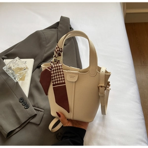 Detail view of beige bucket bag with lychee grain leather and silk scarf handle