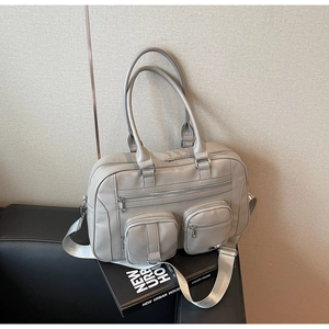 Dettaglio della borsa Boston grigia con tasche multiple su un divano in pelle