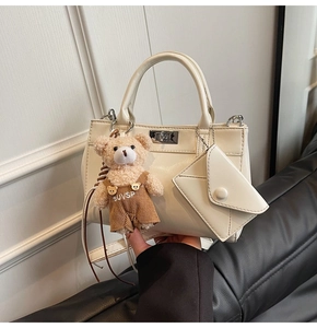 Détail du sac à main en similicuir crème avec fermoir rotatif et charm ourson peluche