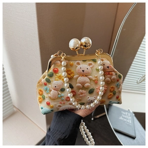 Detail of crochet bear and floral embroidery on a retro shell bag with pearl strap