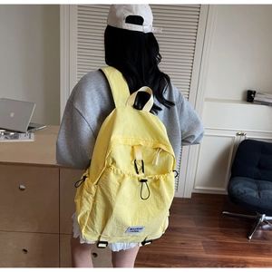 Detail of yellow nylon backpack with drawstring pocket and black carabiner on the back