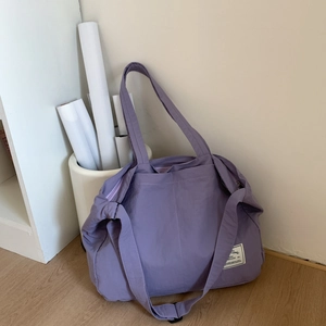 Close-up of lightweight lavender nylon tote bag with adjustable strap and brand logo label